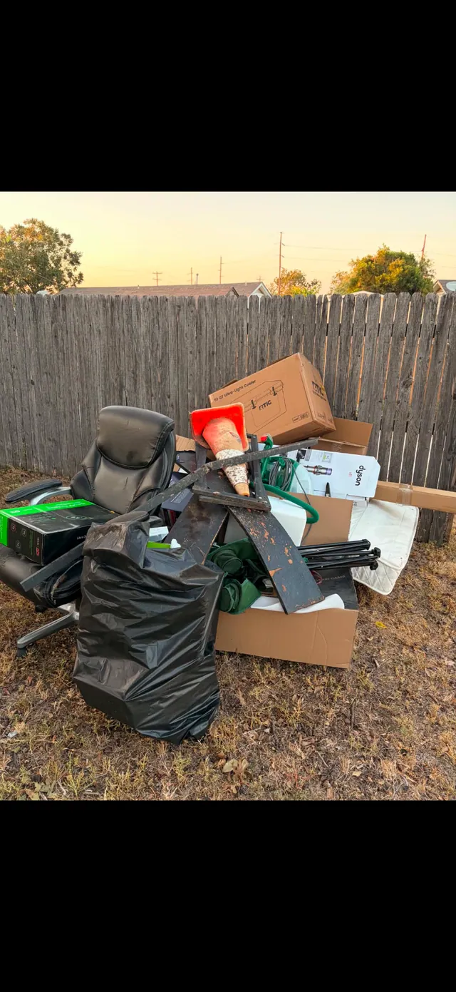 Backyard pile of furniture, boxes, and household junk before removal